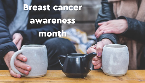 Two people sitting down holding a mug in one hand. Breast cancer awareness month.