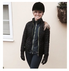 A picture of Hannah, smiling and wearing horse riding gear