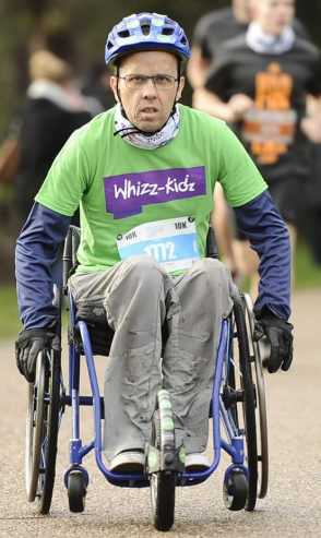 Simon in a wheelchair wearing a green tshirt with the words Whizz-kidz on it