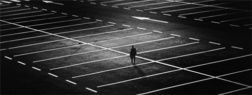 A black and white image of a person standing in an empty carpark