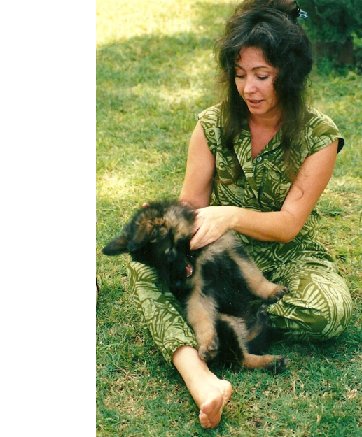  A woman sat on the grass looking down at the dog she is holding