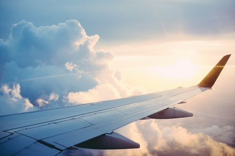  The view of an airplane wing from the aircraft with clouds and sun in the sky