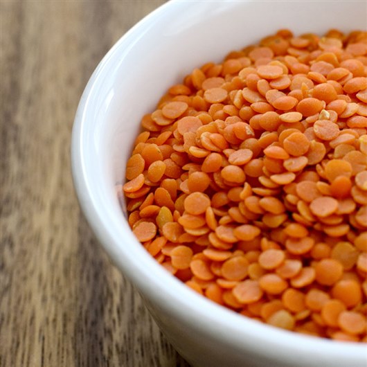 This image shows a bowl of bright orange lentils. 