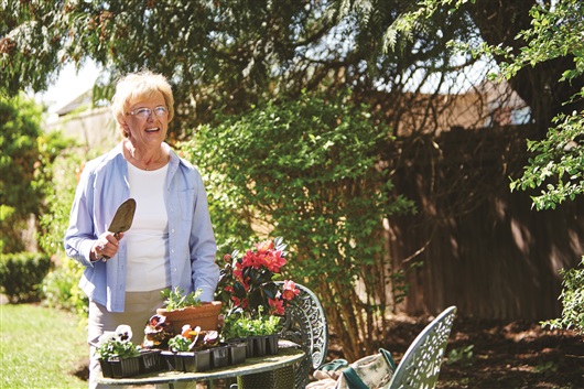 This image shows a middle aged woman potting plants in her garden.