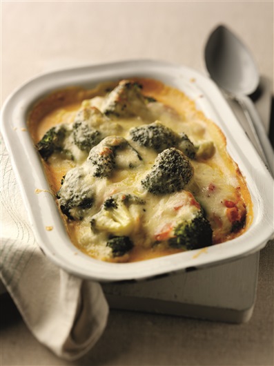 This image shows an oven dish filled with broccoli mornay. The broccoli florets are coming up through the sauce and the top is lightly browned.