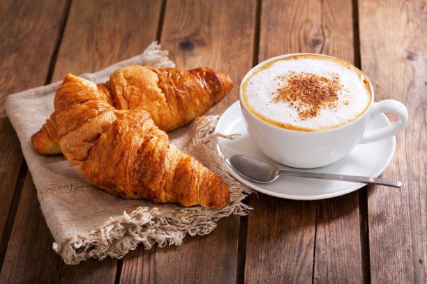 An image of two croissants and a cup of coffee