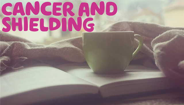 'Cancer and shielding' written in pink over an image of a mug of tea balanced on an open book with a warm blanket surrounding the book. 