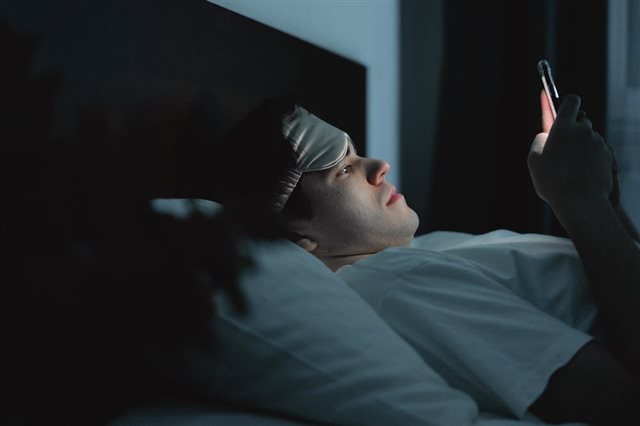 Person laid in bed looking at the phone screen
