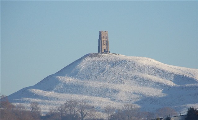 A snowy medieval tower on a hill.