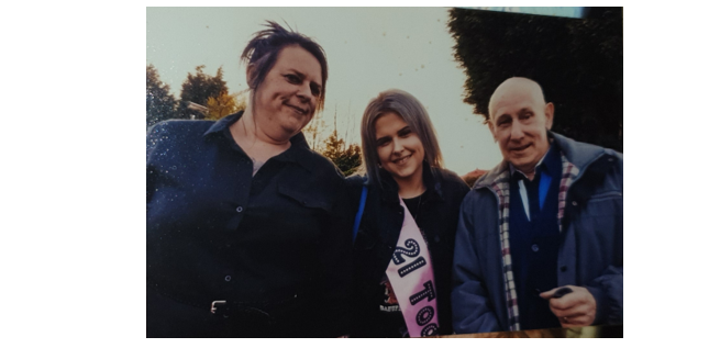 A photograph of LexiT7 and her family, smiling at the camera and surrounded by trees