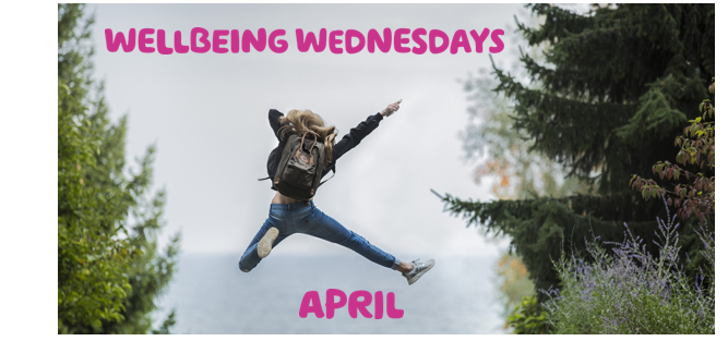  'Wellbeing Wednesday: April' written in pink over a picture of a woman in hiking gear jumping for joy.