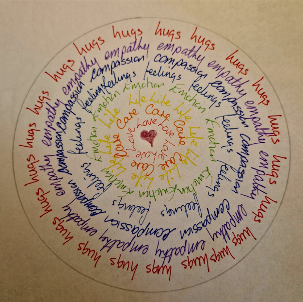 A handwritten mandala with words such as "hugs, love, empathy, life" in multicoloured circles.