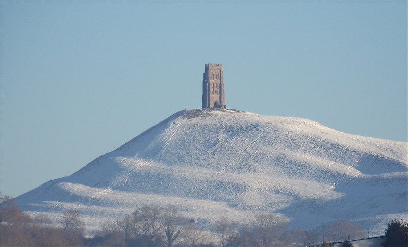 Glastonbury Tor, a single medieval tower on top of a snowy hill.