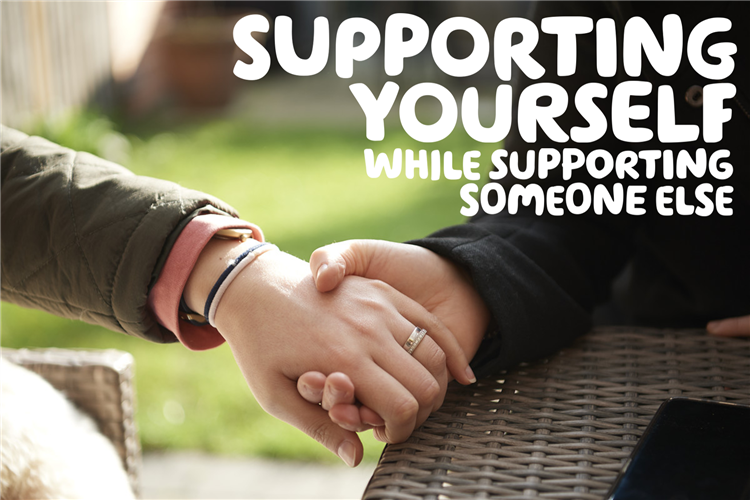 "Supporting someone while supporting someone else" in white over a picture of two women's hands clasped together in the garden. One has a wedding ring visible.