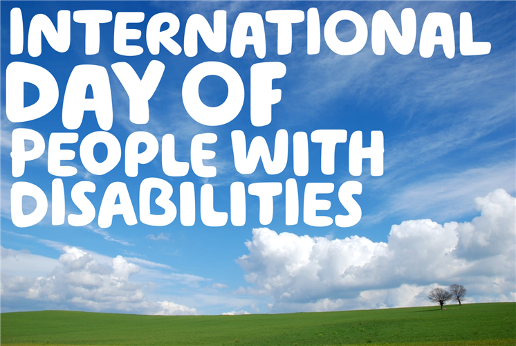 "International day of people with disabilities" written over a blue sky filled with clouds, above a green hill