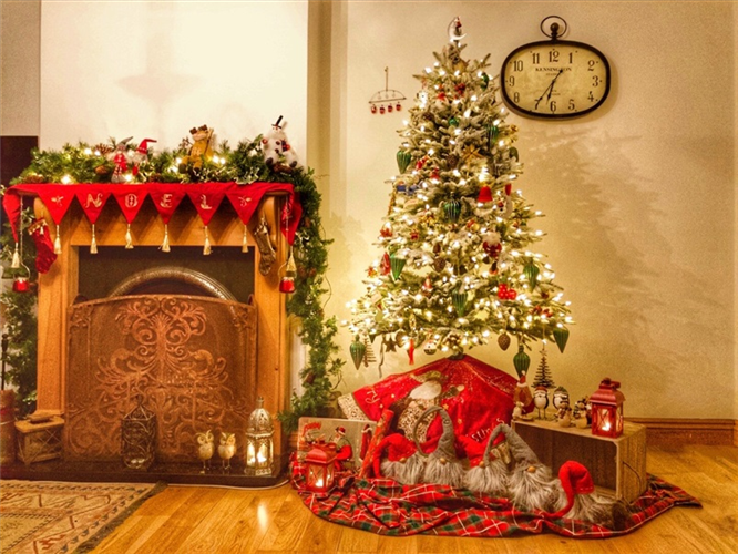 A picture of a cosy fireplace and a Christmas tree, covered in fairy lights.