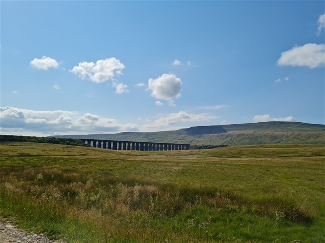 A photo of a long viaduct, moorland and a summer sky